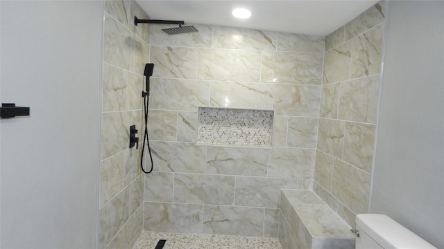 bathroom with a tile shower and toilet