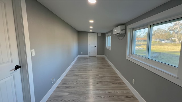 hallway with a wall mounted AC and light hardwood / wood-style floors