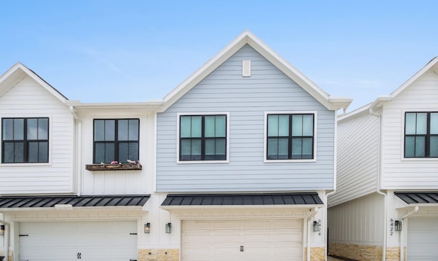 view of property with an attached garage, a standing seam roof, and metal roof