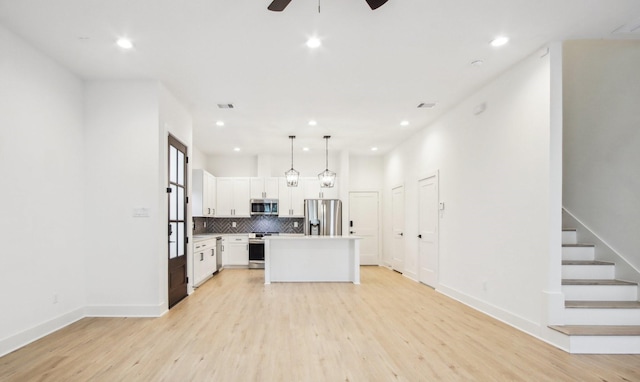 kitchen with stainless steel appliances, white cabinetry, light wood finished floors, and tasteful backsplash