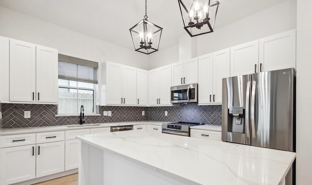 kitchen featuring appliances with stainless steel finishes, backsplash, a sink, and white cabinetry