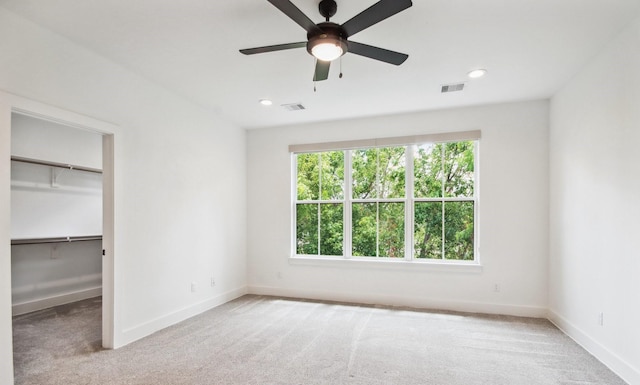 unfurnished bedroom with carpet floors, a walk in closet, visible vents, and baseboards