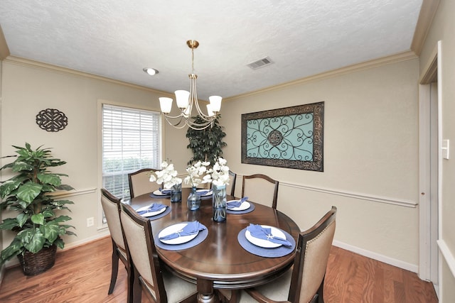 dining room featuring ornamental molding, wood finished floors, visible vents, and a notable chandelier