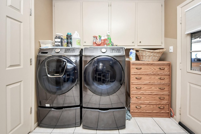 clothes washing area with light tile patterned floors, independent washer and dryer, and cabinet space