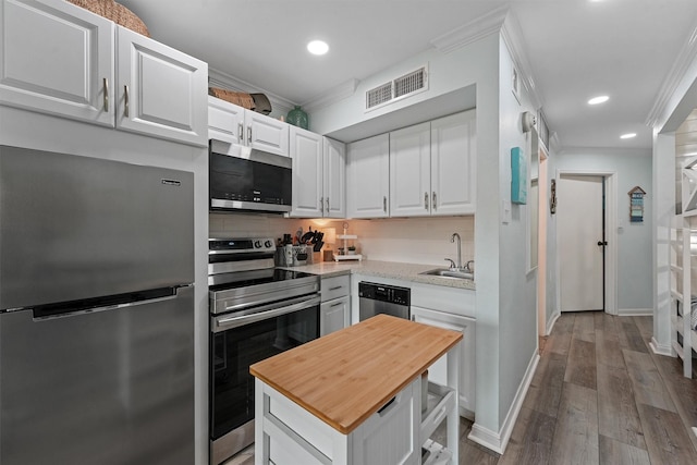 kitchen featuring a sink, visible vents, ornamental molding, appliances with stainless steel finishes, and backsplash