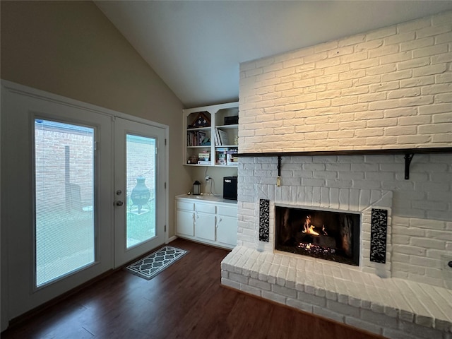 unfurnished living room featuring dark wood-type flooring, vaulted ceiling, french doors, a brick fireplace, and built in shelves