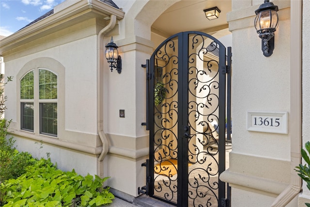 property entrance featuring a gate and stucco siding