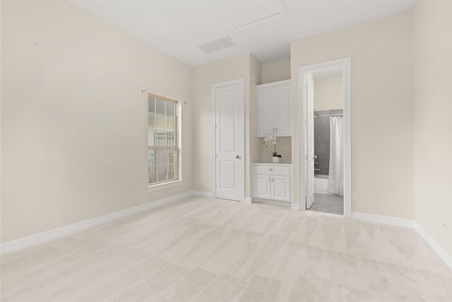 unfurnished bedroom with light colored carpet and connected bathroom