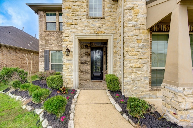 view of exterior entry featuring brick siding and stone siding