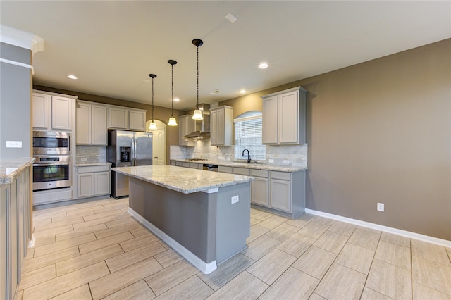 kitchen featuring stainless steel appliances, decorative light fixtures, backsplash, a kitchen island, and a sink