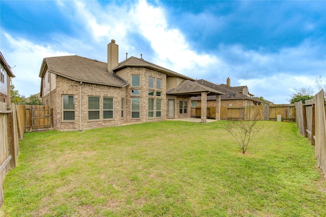 rear view of house featuring brick siding, a yard, and a fenced backyard