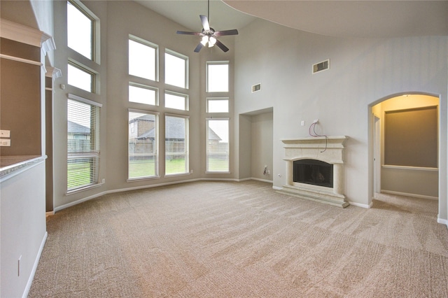 unfurnished living room with light colored carpet, a fireplace with raised hearth, visible vents, and baseboards