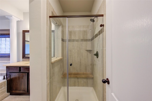 bathroom with ornate columns, a stall shower, and vanity