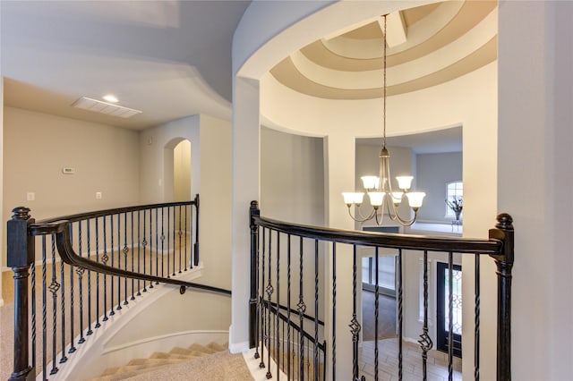 hall with baseboards, an inviting chandelier, visible vents, carpet flooring, and an upstairs landing