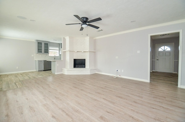 unfurnished living room featuring crown molding, a fireplace, visible vents, and light wood-type flooring