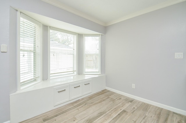 spare room featuring baseboards, crown molding, and light wood finished floors