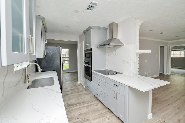 kitchen with visible vents, a sink, decorative backsplash, appliances with stainless steel finishes, and wall chimney range hood