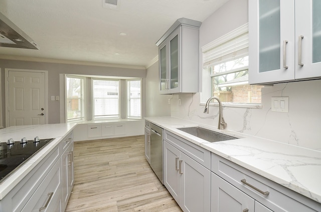 kitchen featuring light wood finished floors, a sink, black electric stovetop, ornamental molding, and stainless steel dishwasher