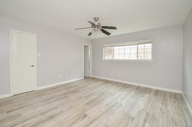 spare room featuring light wood finished floors, a textured ceiling, a ceiling fan, and baseboards