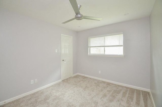 carpeted empty room with a ceiling fan and baseboards