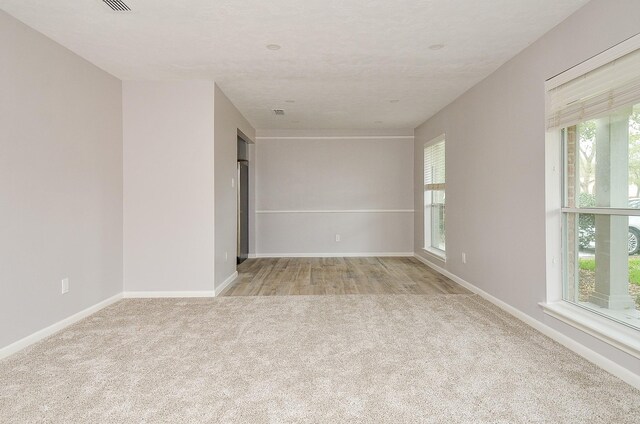 unfurnished room featuring baseboards and light carpet