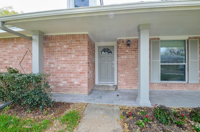 property entrance featuring brick siding and covered porch