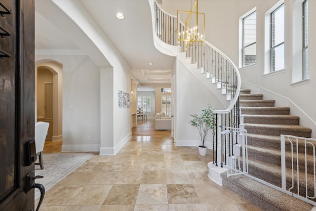 entryway with arched walkways, a notable chandelier, recessed lighting, baseboards, and stairs