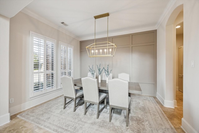 dining area featuring ornamental molding, visible vents, a decorative wall, and baseboards