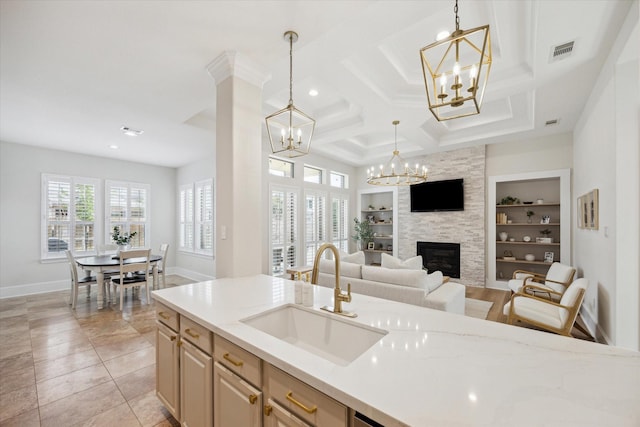 kitchen featuring built in shelves, a sink, visible vents, hanging light fixtures, and an inviting chandelier