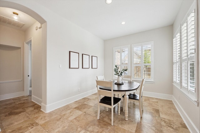 dining area featuring arched walkways, recessed lighting, and baseboards