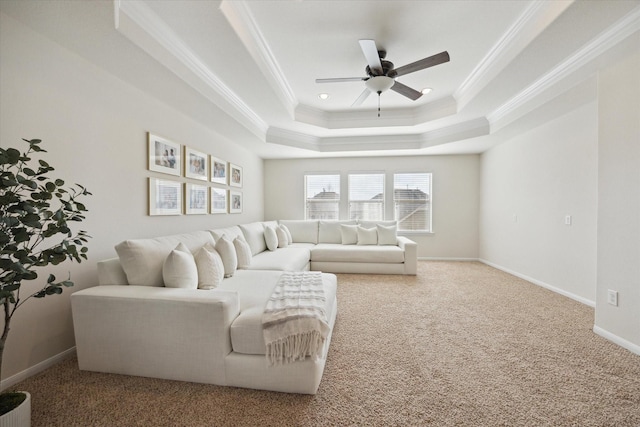 carpeted living room featuring baseboards, a raised ceiling, a ceiling fan, and crown molding