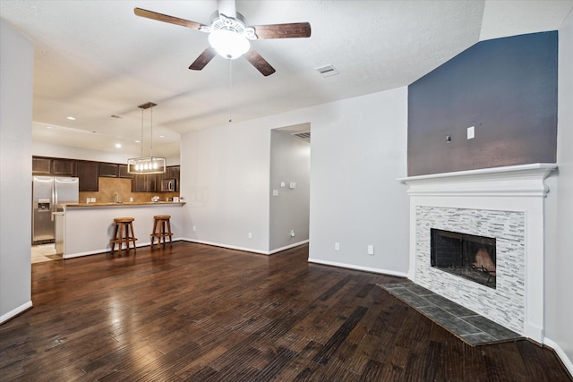 living area featuring ceiling fan, a fireplace, baseboards, and dark wood-style flooring