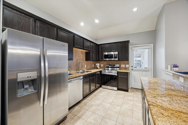 kitchen featuring light tile patterned floors, a sink, appliances with stainless steel finishes, light stone countertops, and tasteful backsplash