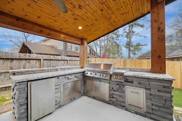 view of patio featuring an outdoor kitchen, a fenced backyard, and a grill