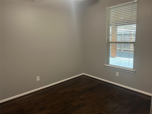 spare room featuring baseboards and wood finished floors