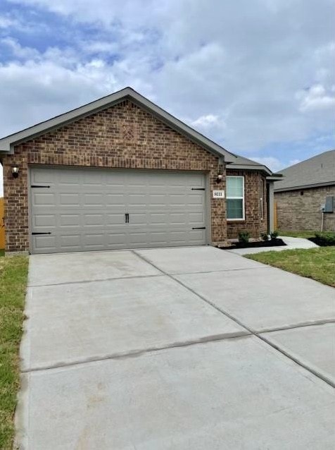 ranch-style home with a garage, concrete driveway, and brick siding