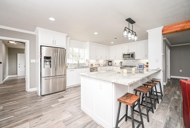1133 Peebles St, Hempstead, TX 77445 - kitchen featuring appliances with stainless steel finishes, white cabinets, tasteful backsplash, light wood-type flooring, and ornamental molding
