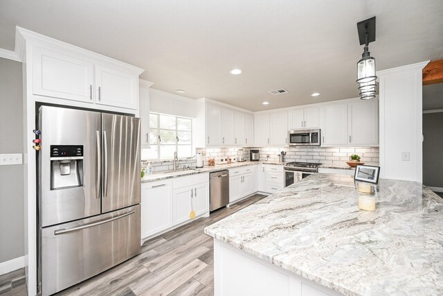 kitchen featuring stainless steel appliances, visible vents, white cabinets, light stone countertops, and pendant lighting