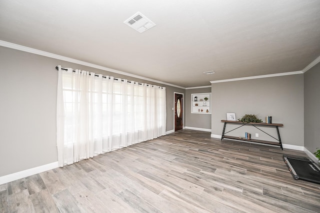 unfurnished room with light wood-style floors, visible vents, crown molding, and baseboards