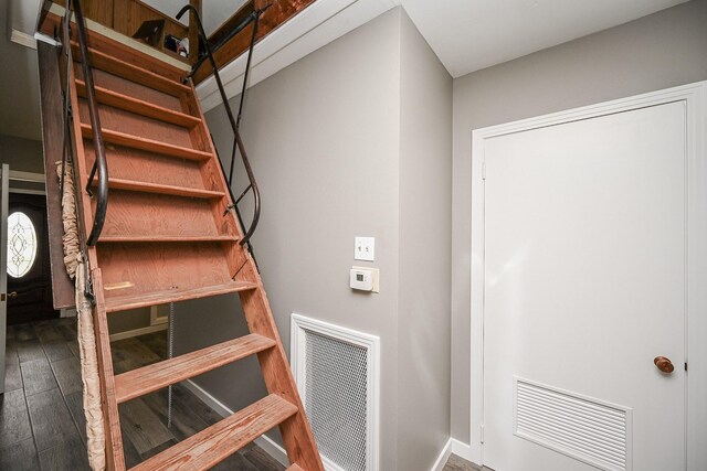 staircase with visible vents, baseboards, and wood finished floors