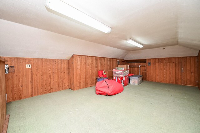 bonus room with lofted ceiling, light colored carpet, and wooden walls