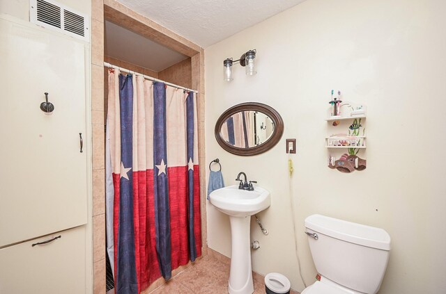 full bathroom featuring visible vents, a shower with shower curtain, toilet, a textured ceiling, and tile patterned flooring