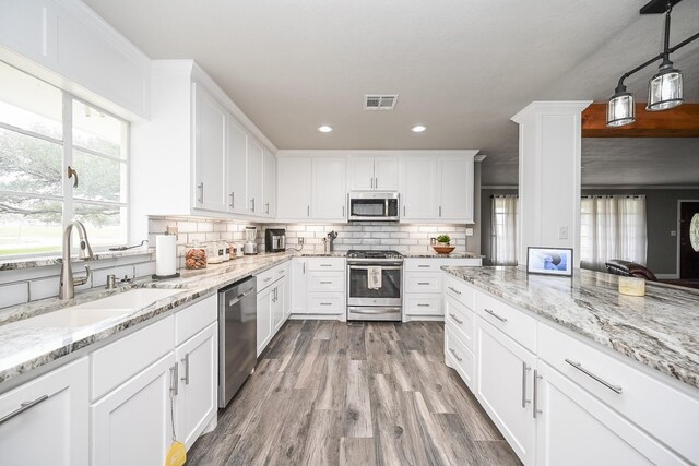 kitchen with a sink, visible vents, white cabinetry, appliances with stainless steel finishes, and decorative backsplash