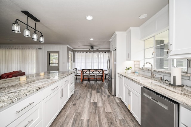 1133 Peebles St, Hempstead, TX 77445 - kitchen with appliances with stainless steel finishes, a sink, a ceiling fan, wood finished floors, and white cabinets