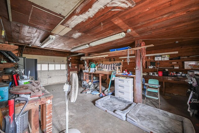 misc room with a garage, wood ceiling, unfinished concrete floors, and a workshop area