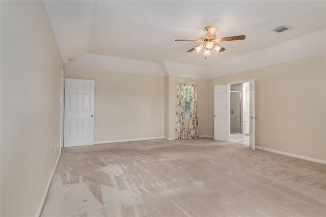 empty room featuring a tray ceiling, ceiling fan, vaulted ceiling, and light carpet