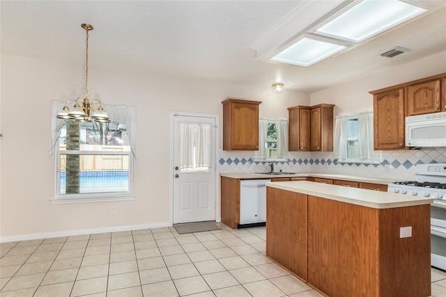 kitchen with sink, white appliances, hanging light fixtures, and decorative backsplash