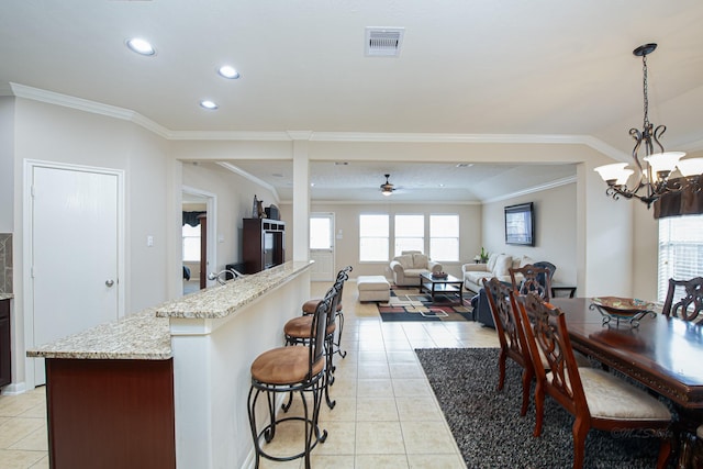 522 Arbor Green Ln, Rosenberg, TX 77469 - kitchen with light tile patterned flooring, recessed lighting, ornamental molding, a kitchen bar, and a ceiling fan