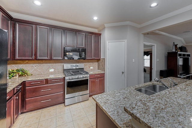 kitchen with black microwave, stainless steel gas stove, a sink, tasteful backsplash, and light stone counters
