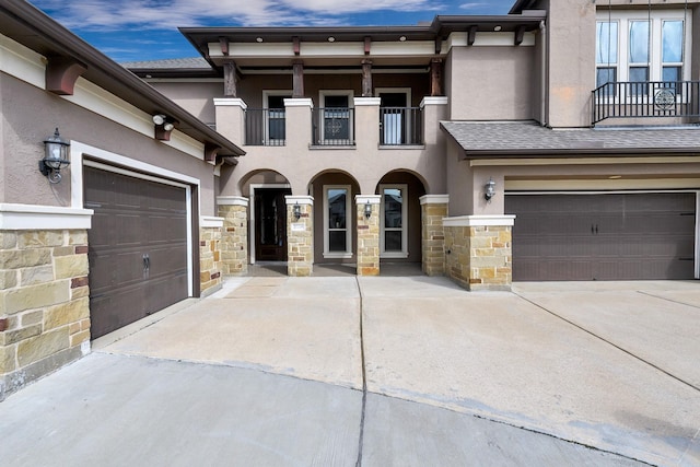 view of front of property with a garage, concrete driveway, stone siding, and stucco siding